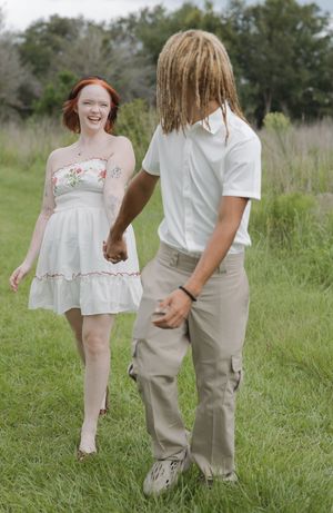 Candid shots of couple walking and playing in tall grass during a summer photoshoot.