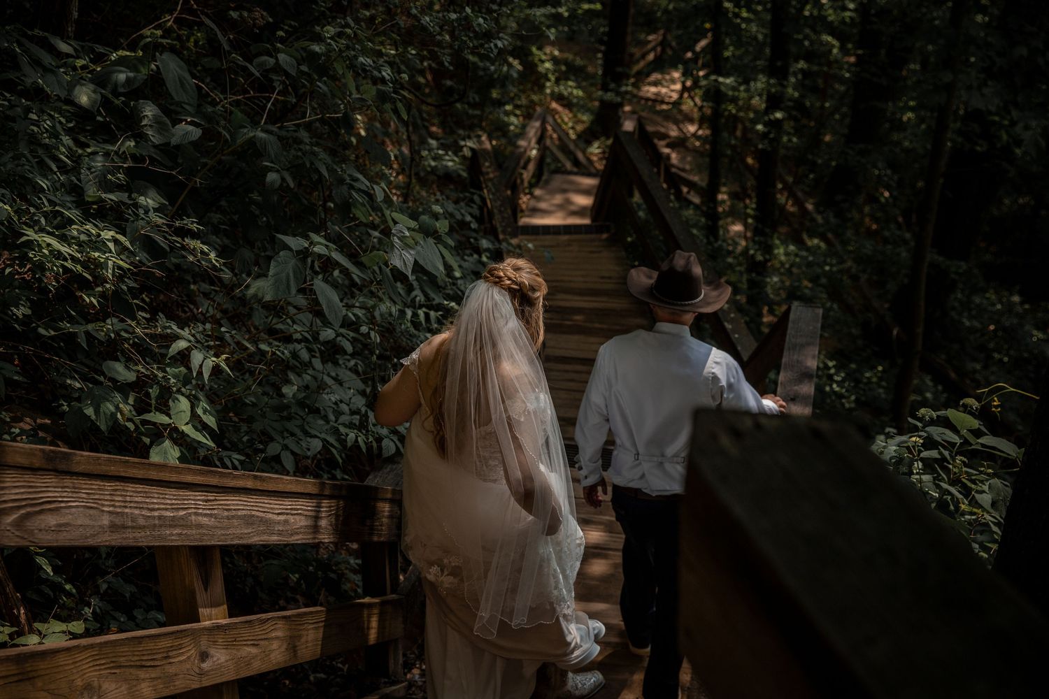 newly weds have their wedding photographer capture a documentary style portrait as they hike down a trail at cloudland state park in georgia