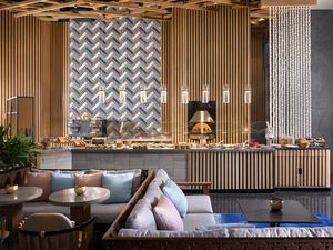 Modern luxury hotel lobby interior with wooden slat walls, geometric patterns, and contemporary furniture design.