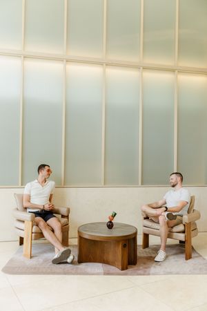 A sequence of images showing a person reclining in a minimalist chair with wood frame against a light colored wall.
