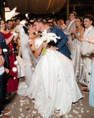 Group of wedding guests dip dancing in synchronized fashion at a reception, creating a playful party atmosphere.