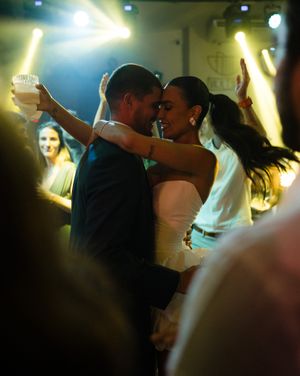 Silhouetted dancers embrace on a dimly lit dance floor with golden lighting creating a romantic atmosphere.
