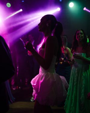A dance floor illuminated with vibrant purple and green lighting during a nighttime celebration event creates an electric atmosphere.