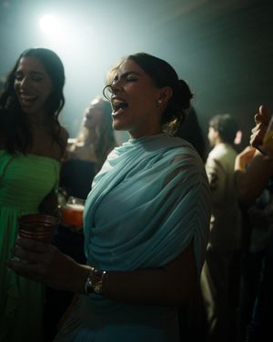 People enjoying a lively party atmosphere with moody lighting and draped fabric visible in the background.