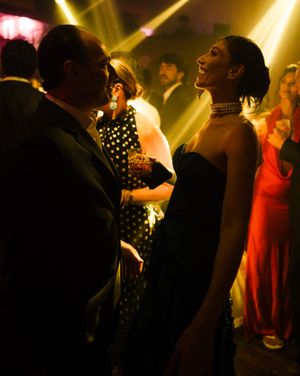 People dancing under dramatic golden spotlights in a dark nightclub atmosphere create a lively party scene.