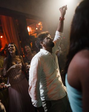 Partygoers dance and celebrate at a nightclub with moody lighting and glowing orange atmosphere.