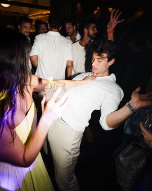 People dancing and socializing at a dark nightclub with purple mood lighting in the background.