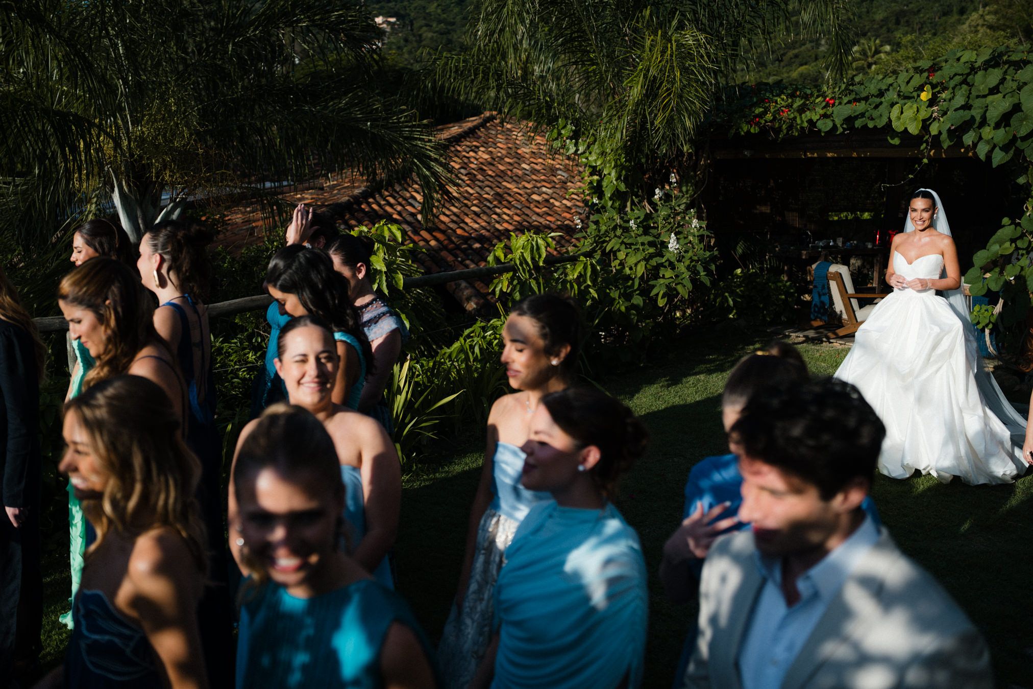 Guests at an outdoor wedding joyfully dance and celebrate during a reception in a lush garden setting.