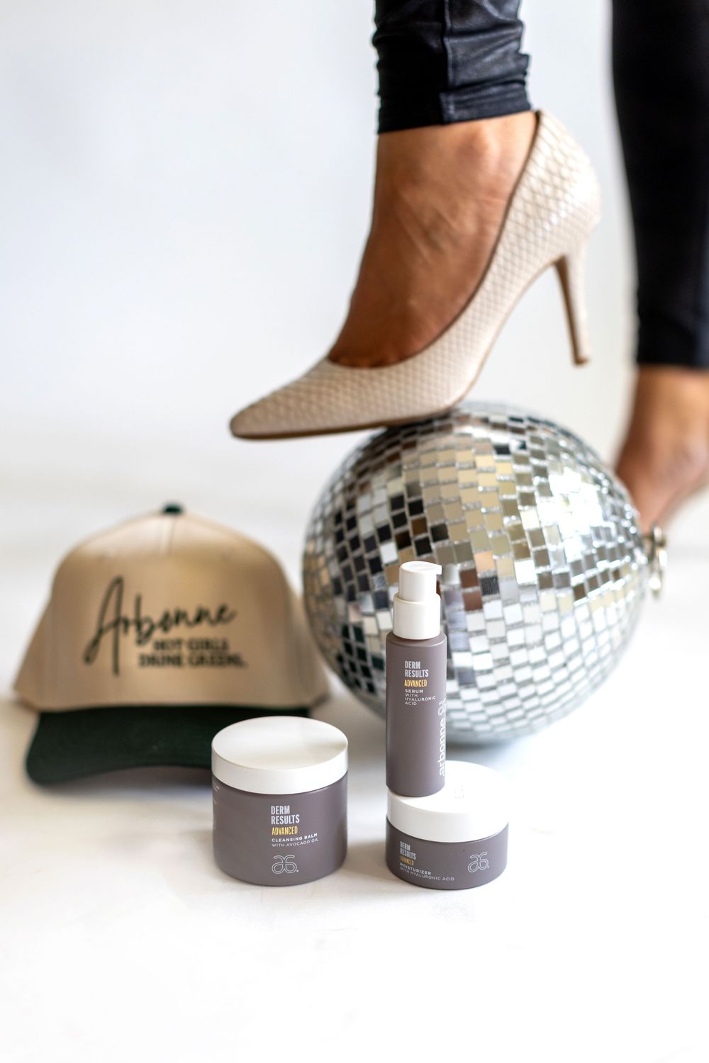 A silver disco ball next to beauty product jars and bottles on a white surface.