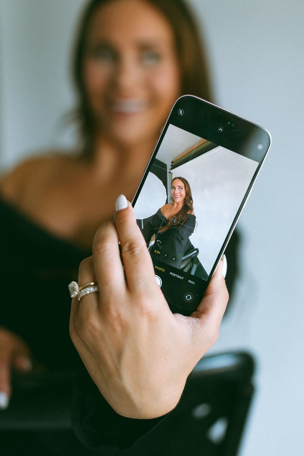 A series of close-up shots showing hands holding a black smartphone device against a soft, light background.
