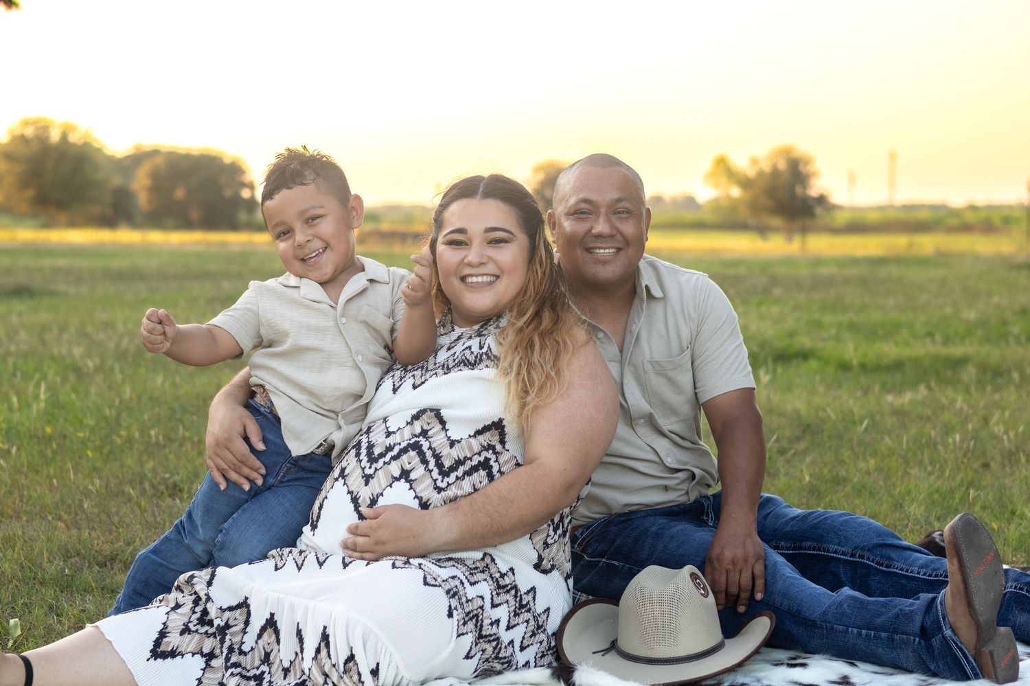 Family enjoying sunset picnic in grassy field with warm golden lighting.