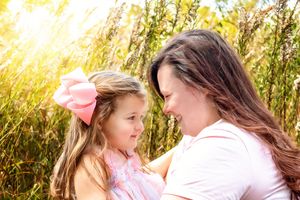 Intimate outdoor family photoshoot among tall grass at golden hour.
