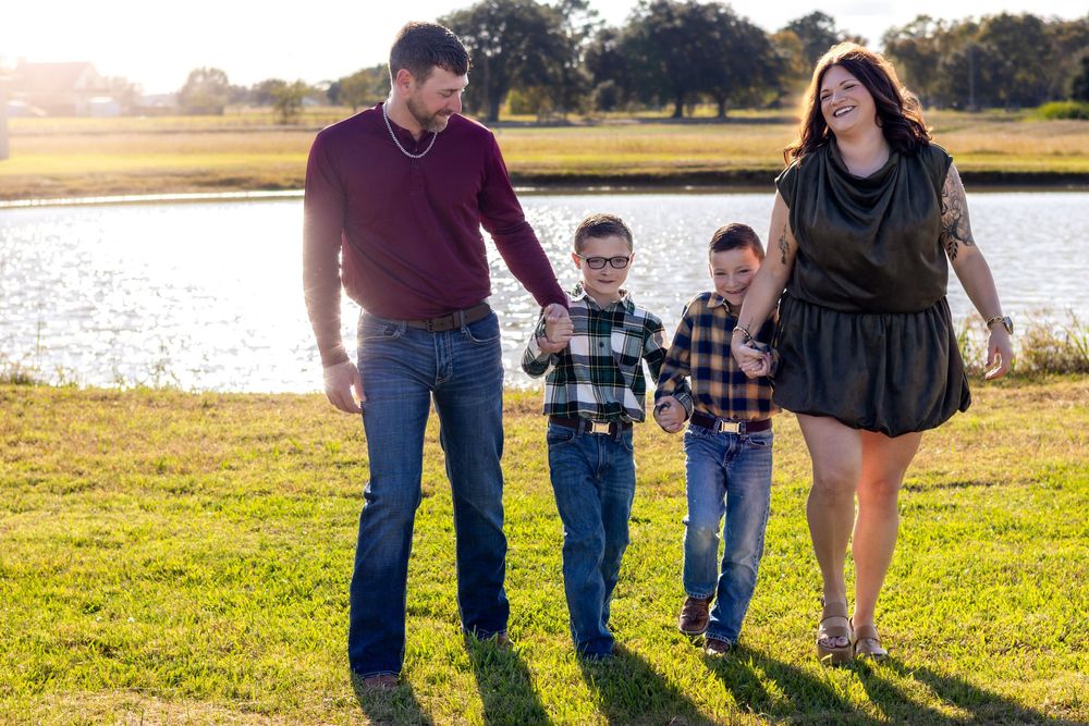 Family walking together in a grassy field at sunset with golden sunlight illuminating the scene.