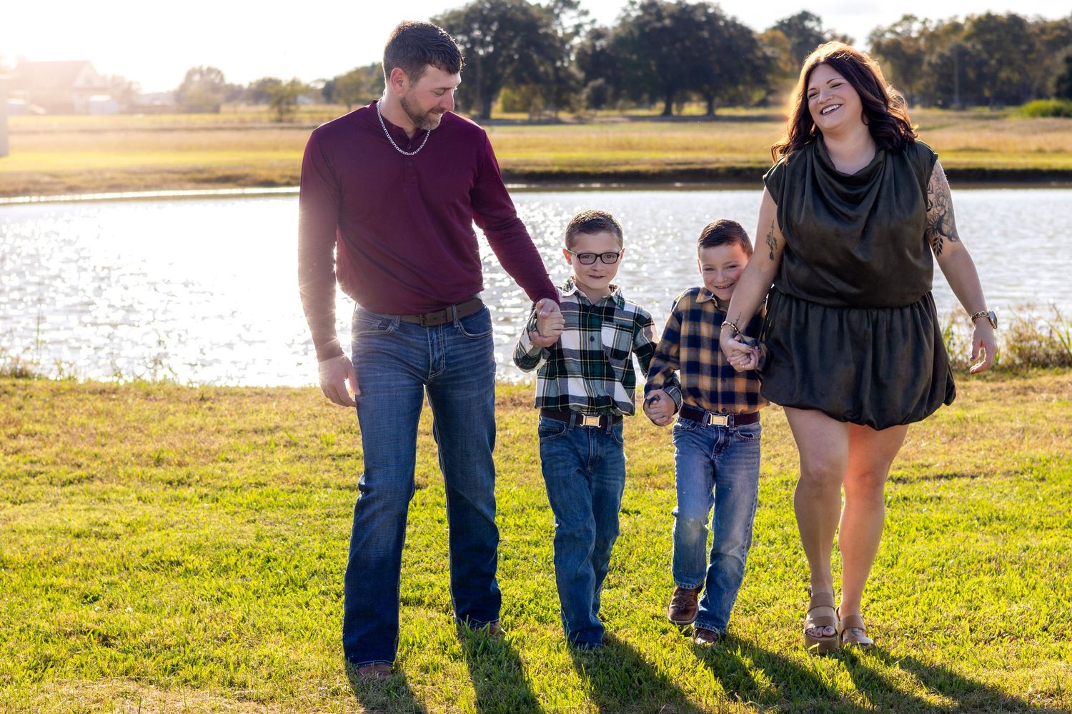 Family walking together in a grassy field at sunset with golden sunlight illuminating the scene.