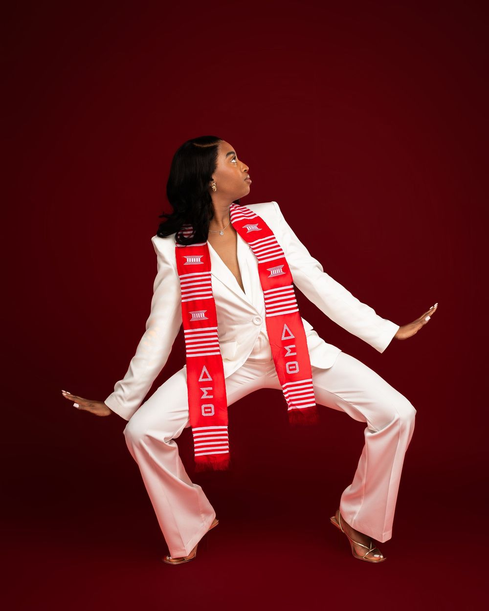 Dynamic studio shots with red backdrop showing movement in white outfit with red DST stole.