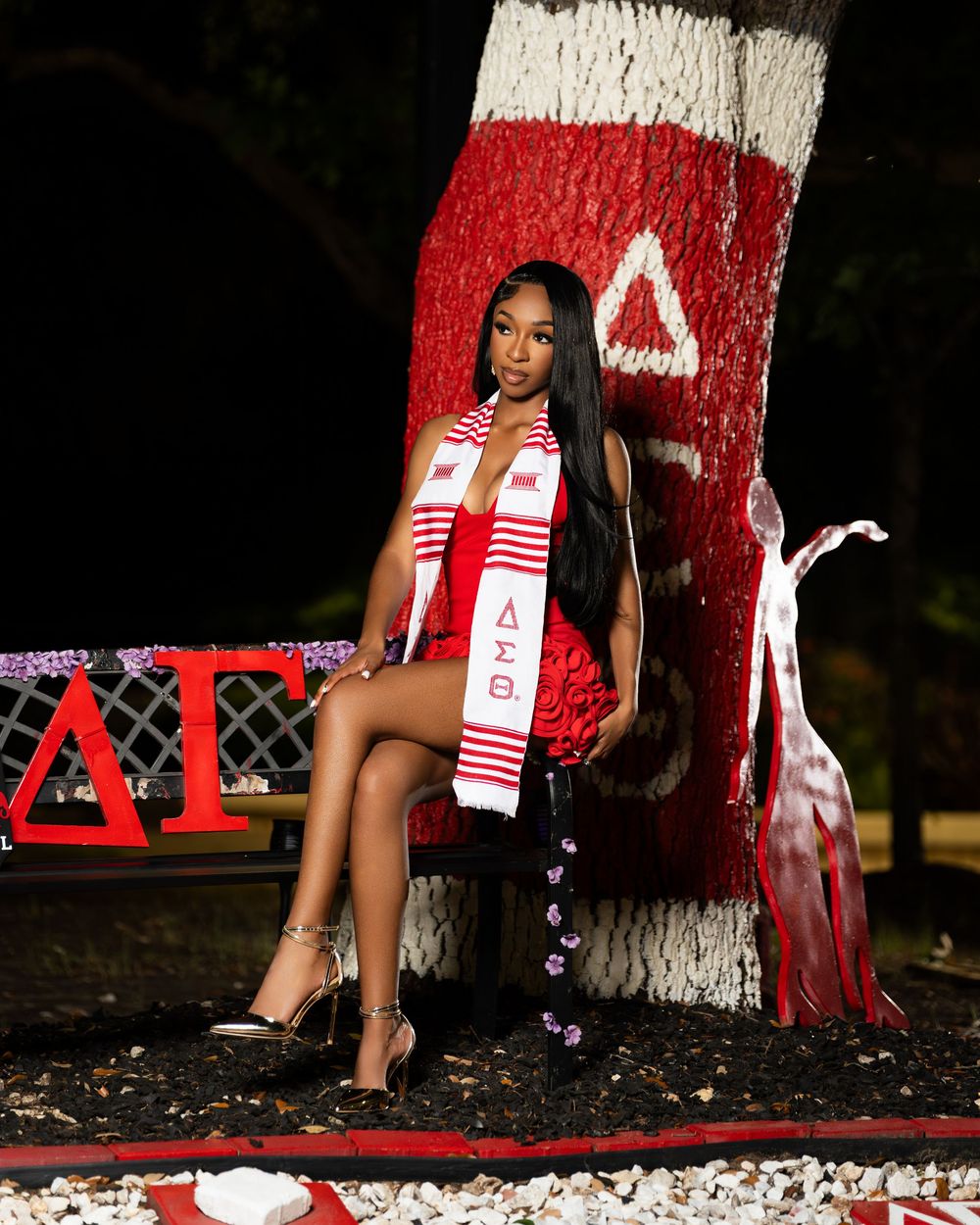 Graduation photoshoot featuring red and white themed props against painted tree trunk.