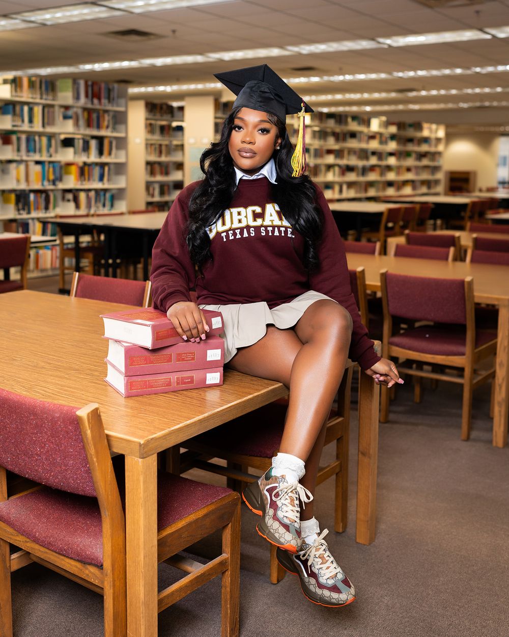College library photoshoot featuring maroon university apparel and casual sneakers.