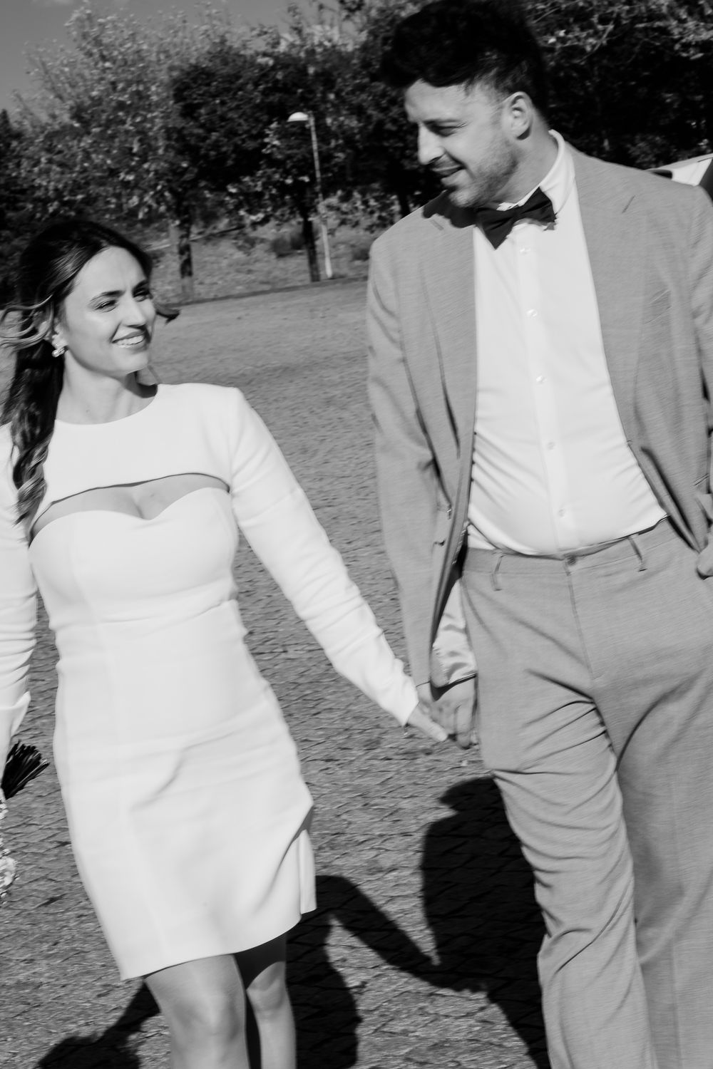 A candid black and white photo of a couple walking and laughing together outdoors.