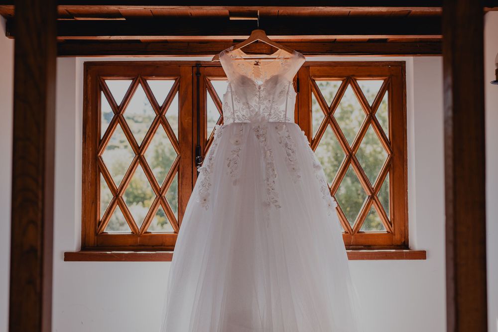 Wedding dress displayed in a rustic room with diamond-paned windows.