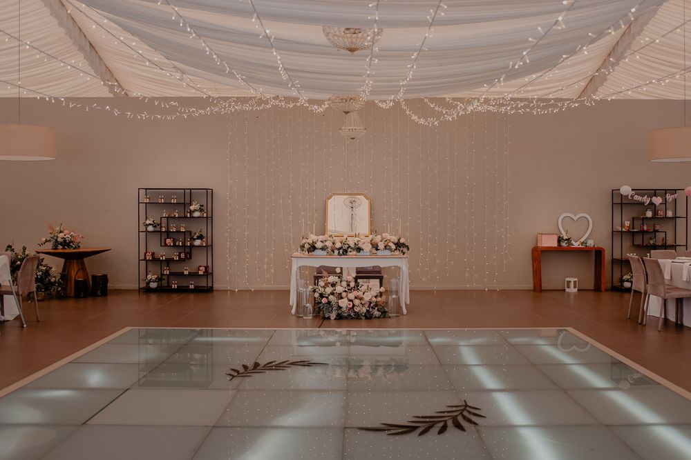 Empty wedding venue with white ceiling drapes and string lights creating an elegant atmosphere.