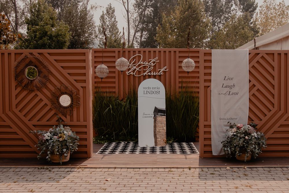 Modern outdoor event entrance with geometric wood panels and decorative archway in warm terracotta tones.