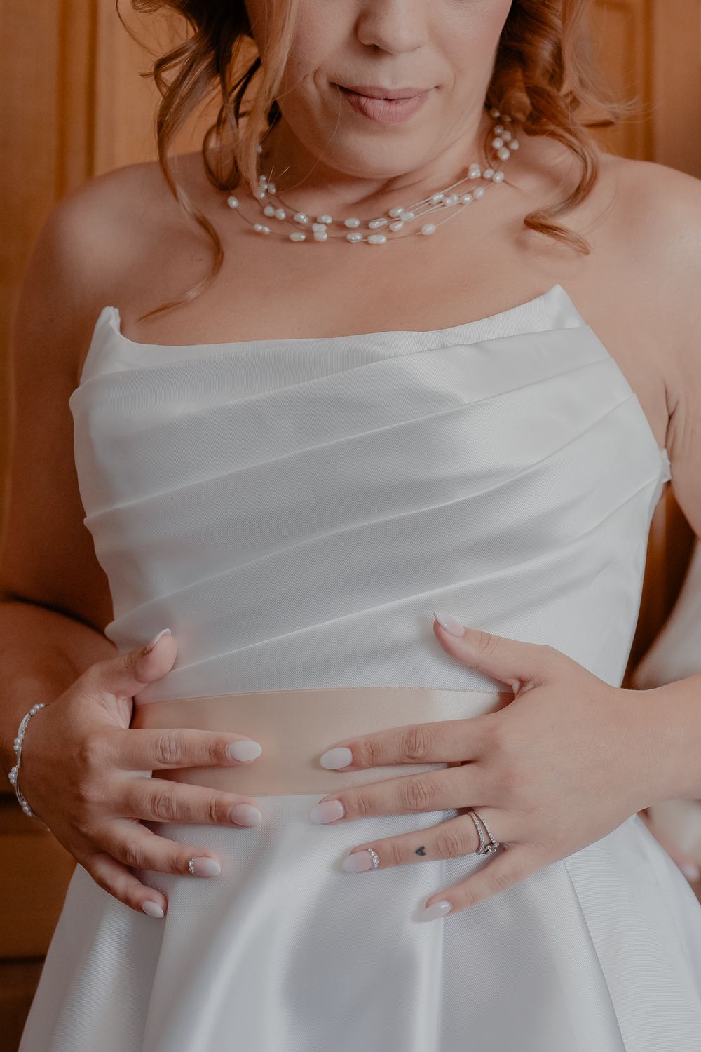 Detail shot of pearl necklace and white wedding dress bodice.