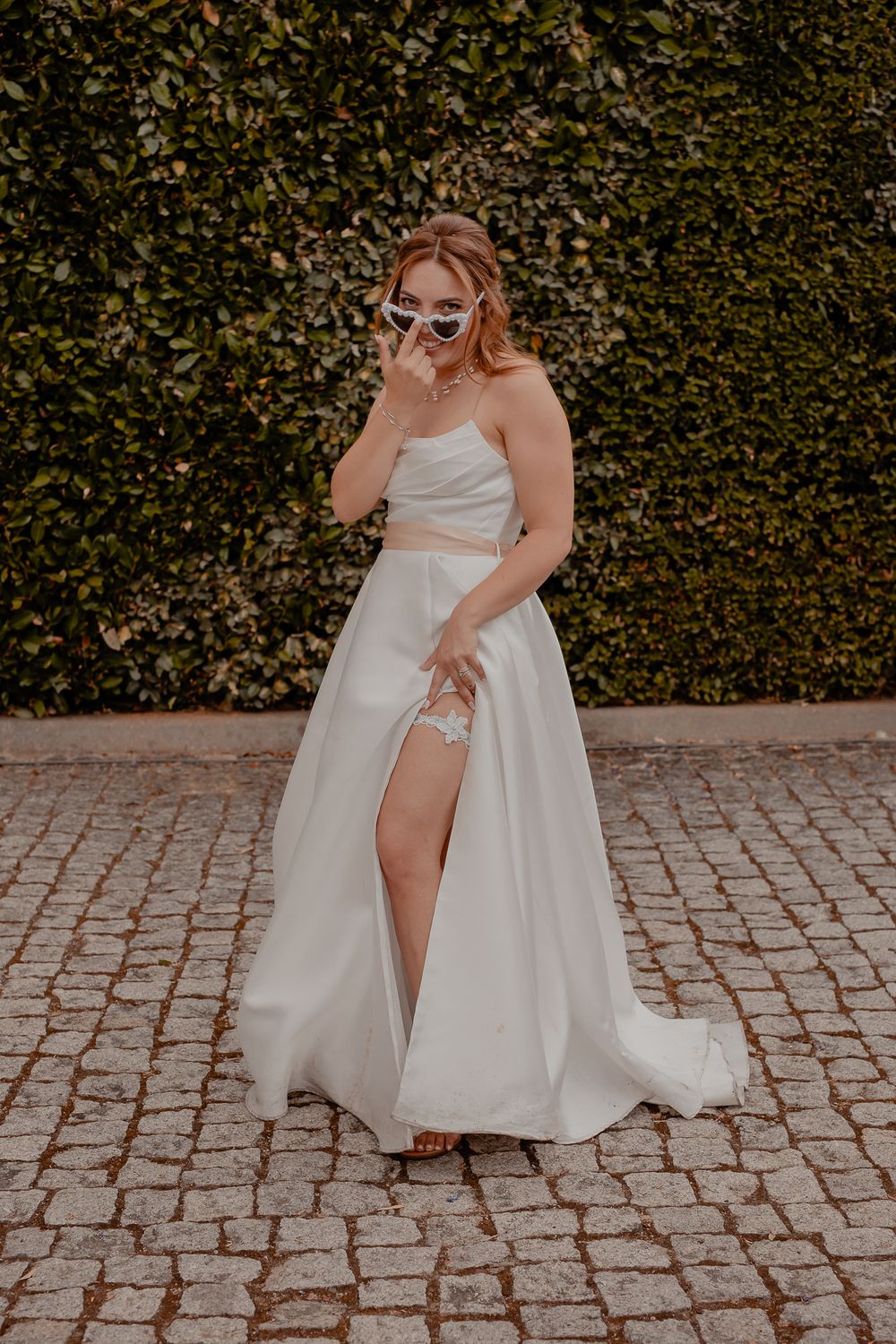 Bride showing off wedding dress details while twirling on cobblestone patio.