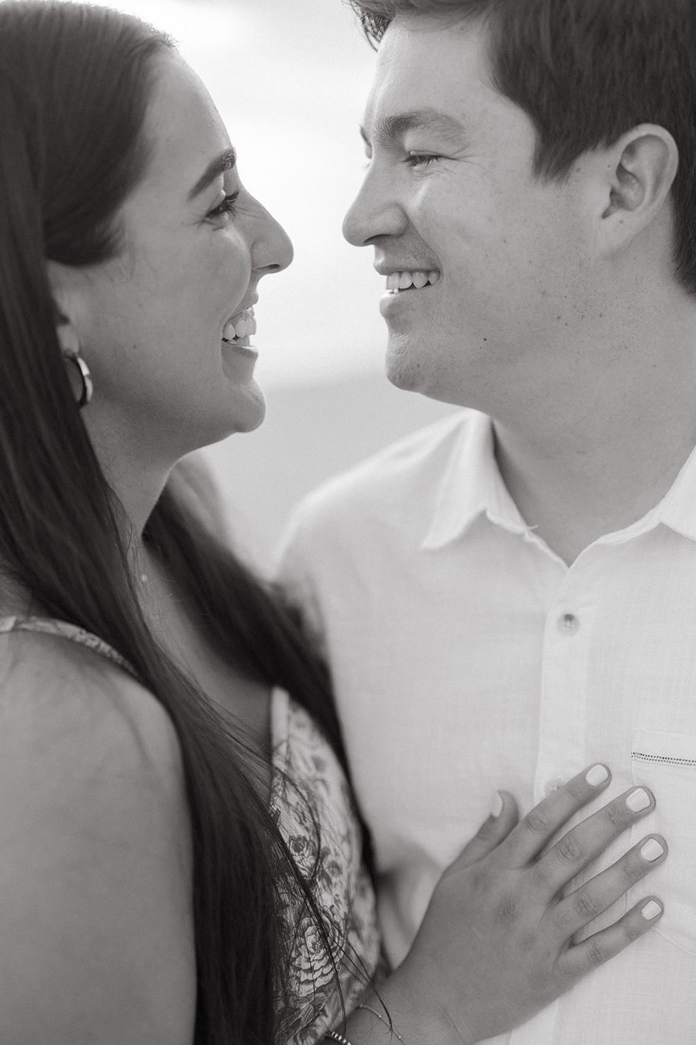 A candid black and white close-up of a couple laughing together in an intimate moment.