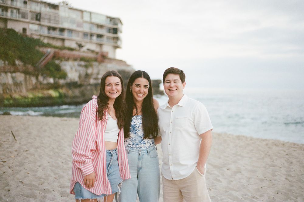 A group enjoying a relaxed afternoon together on a scenic beach with coastal buildings in the background.