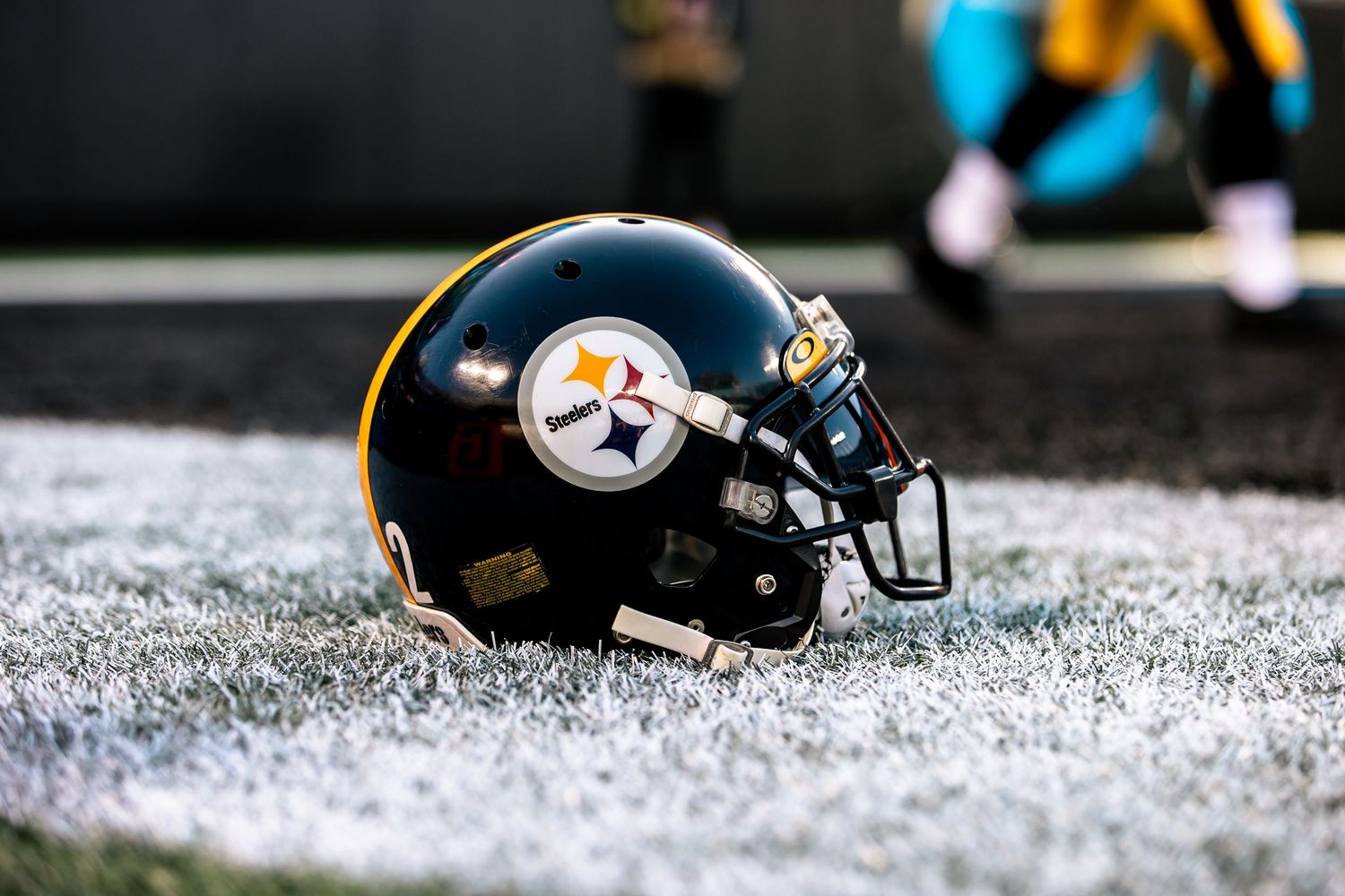 Pittsburgh Steelers black and gold helmet rests on frost-covered turf before game.