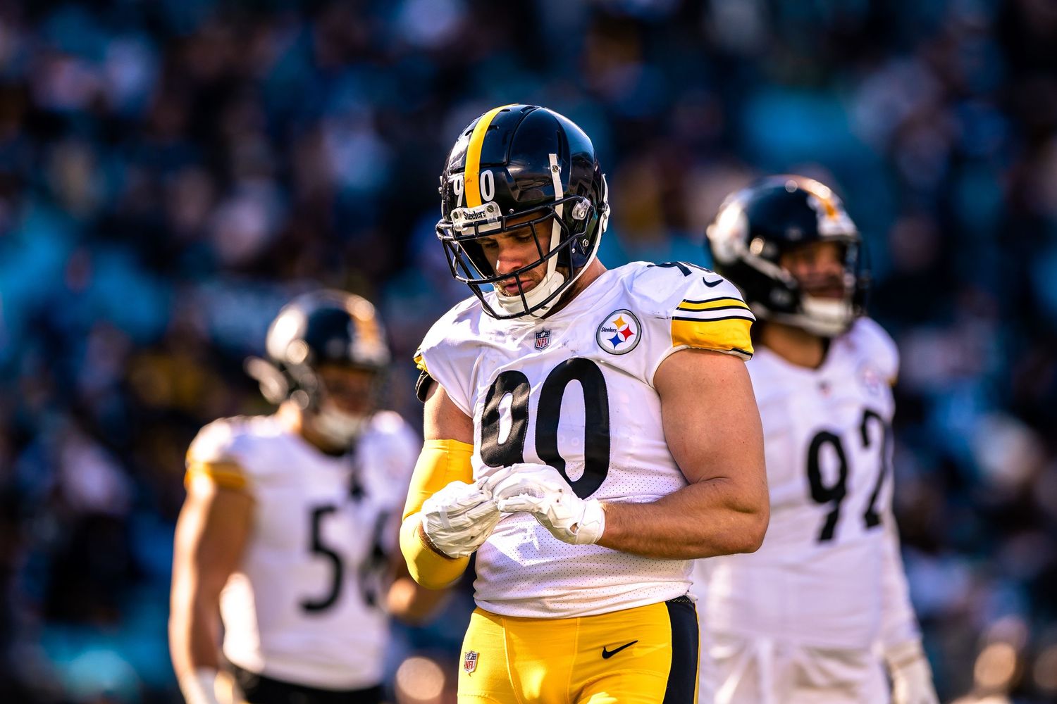 Pittsburgh Steelers player #90 stands on the field during an NFL game in yellow and white uniform.