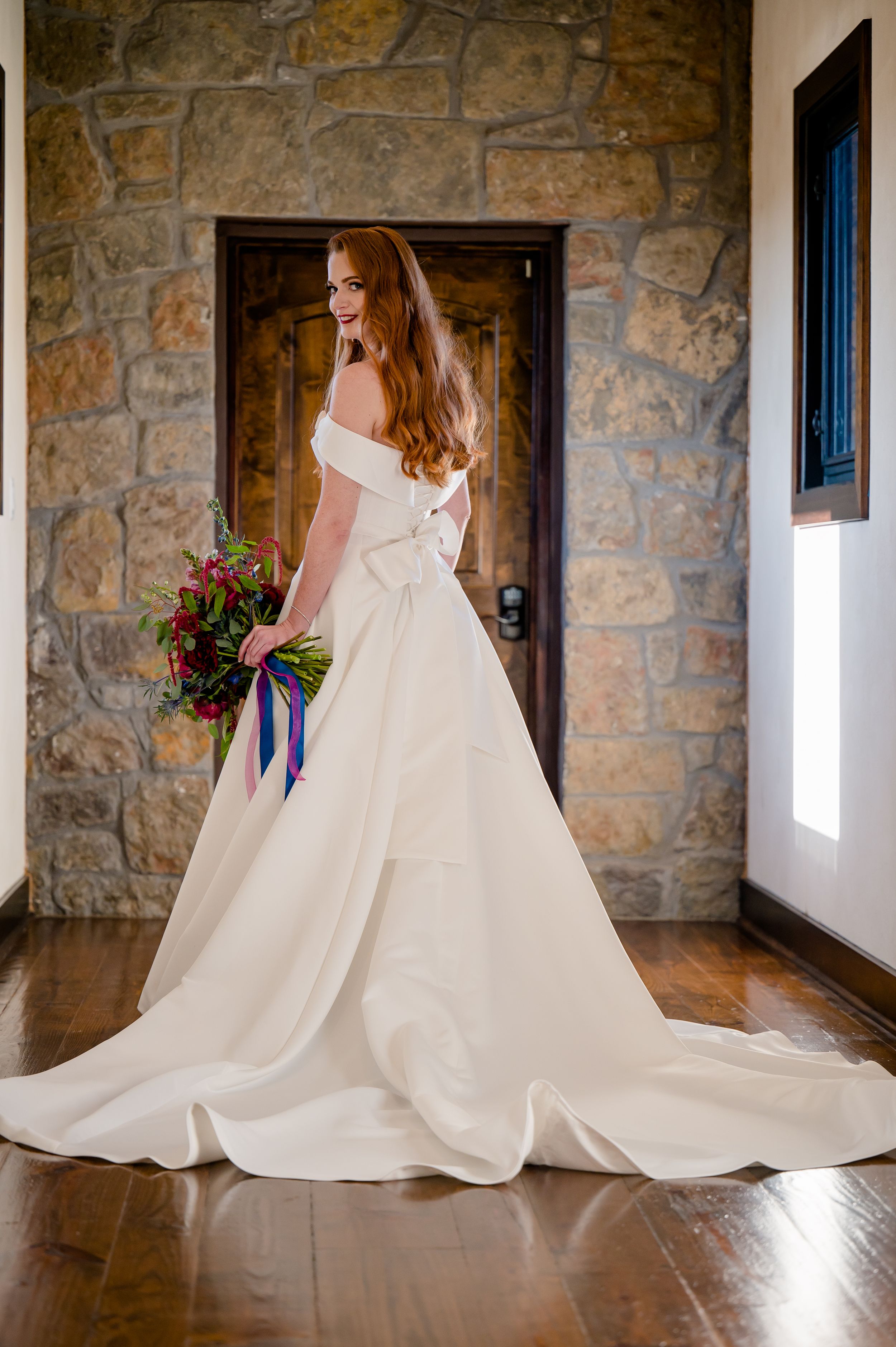A stunning ballgown wedding dress with dramatic train flows across a rustic stone and wood floor in a series of elegant poses.