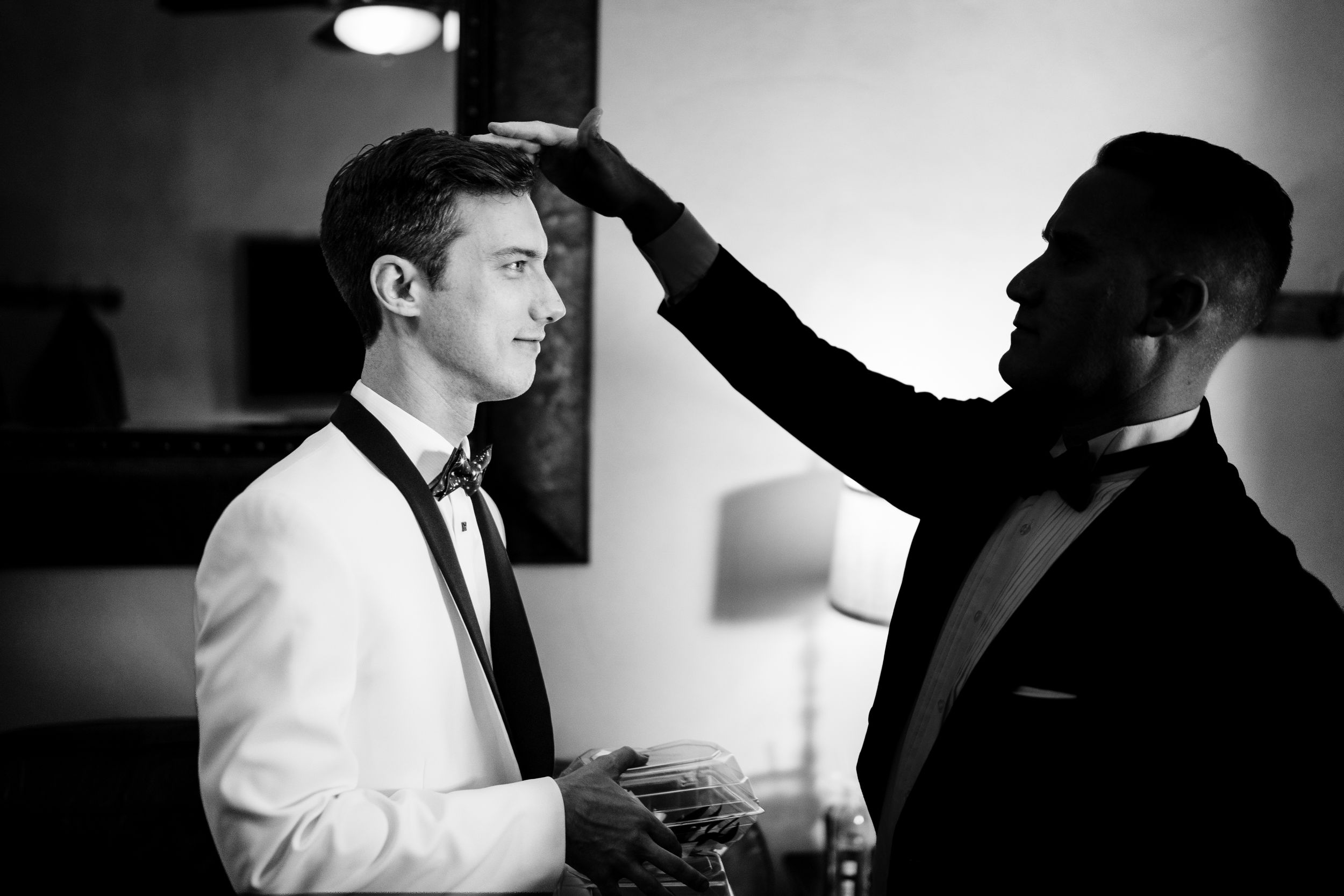 Dramatic black and white cinematography captures intimate moments with formal attire in artistic fashion.