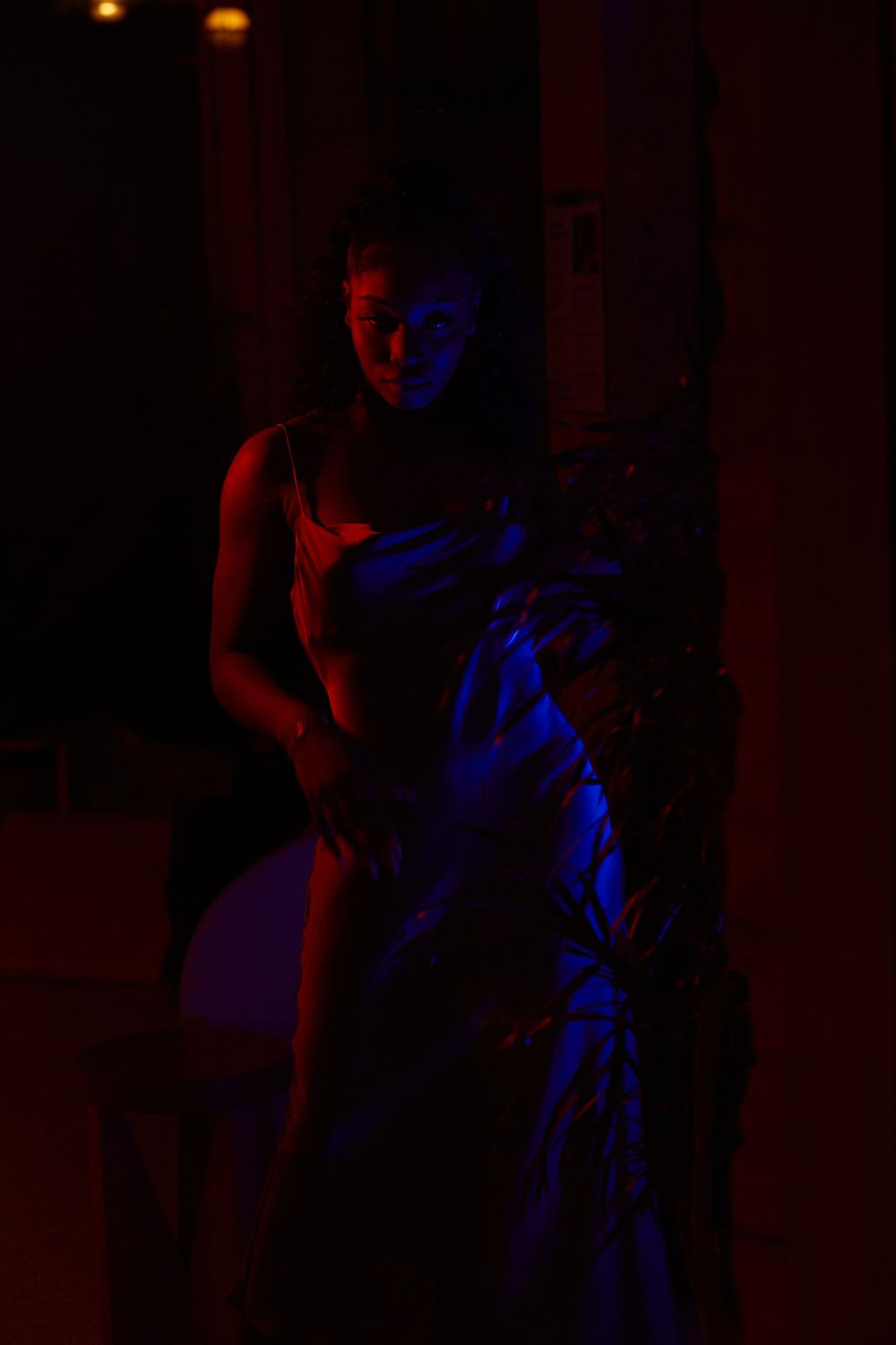 A silhouette in red and blue lighting creates a dramatic nighttime portrait.