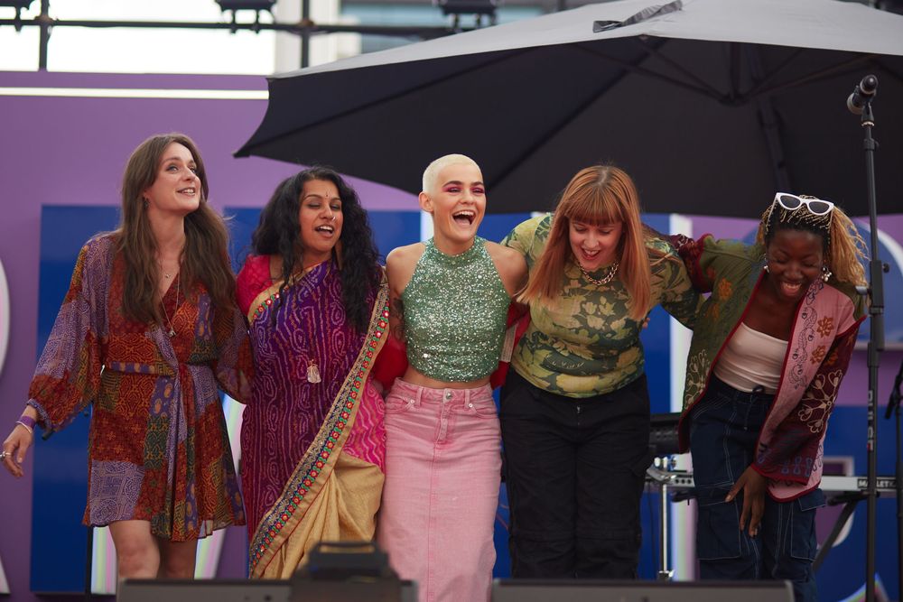 A group of performers pose together on stage at an outdoor event.
