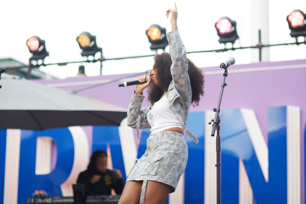 Dancing figure in athletic wear moves energetically against a blue backdrop during performance.
