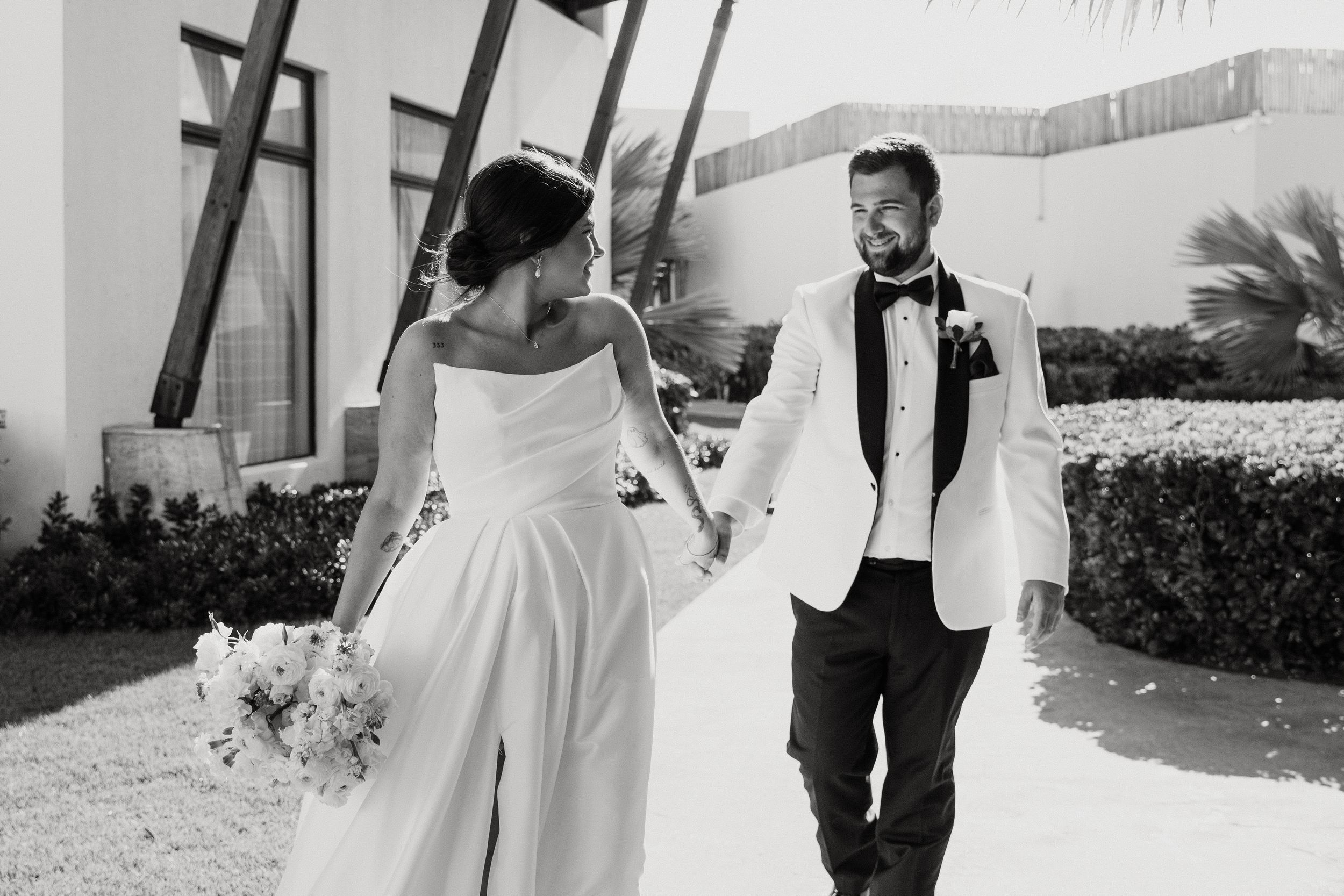 Black and white photo of newlyweds walking together in formal attire at Dreams Macao