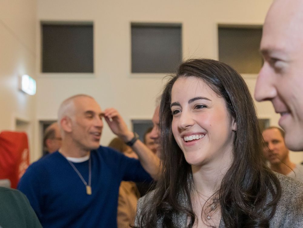 People laughing and enjoying themselves at a social gathering in an indoor setting.