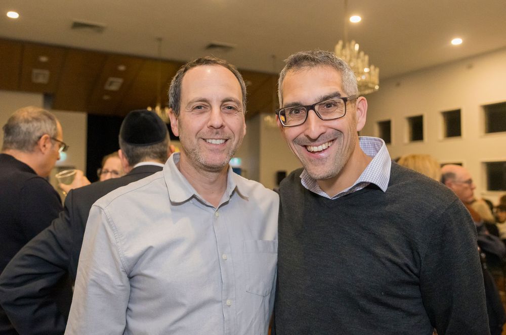 Business professionals stand together in conversation at a networking event in a bright modern office space.