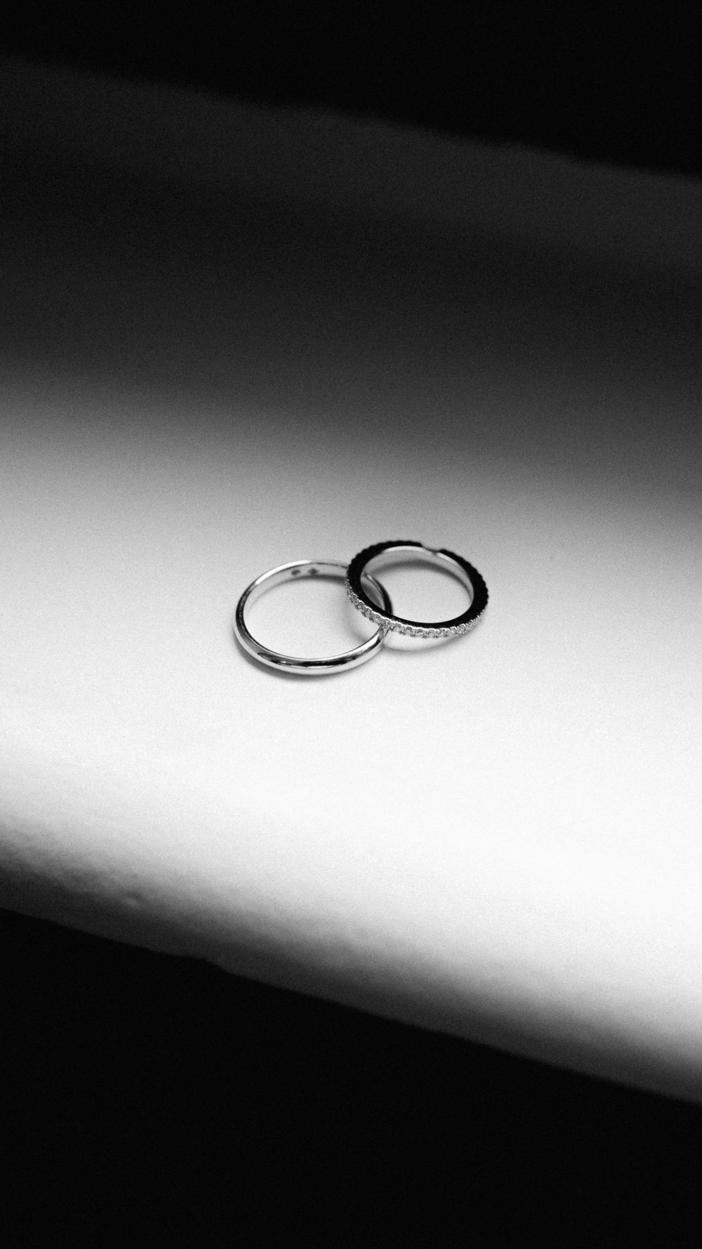 Artistic black and white photograph of wedding rings with dramatic lighting.