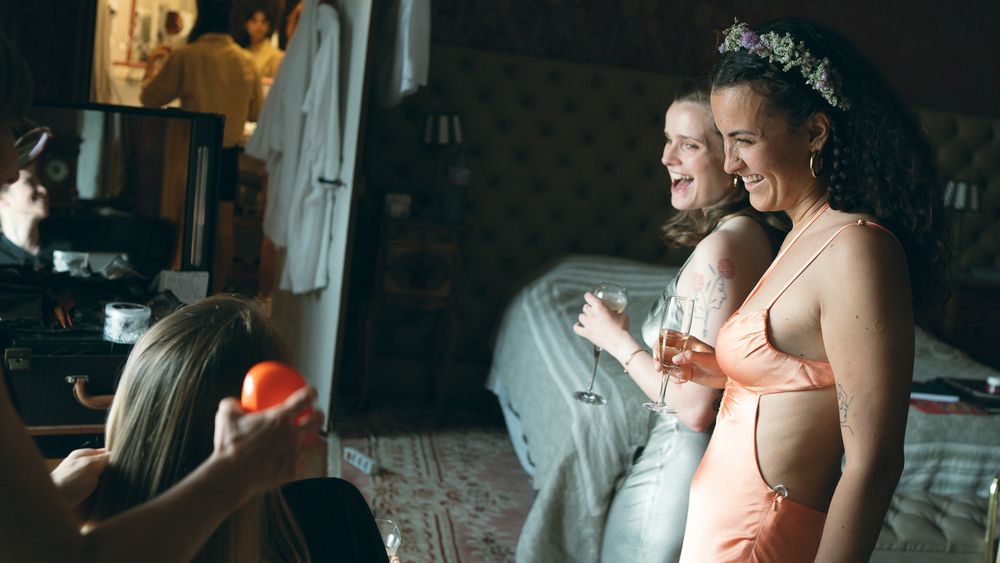 Wedding preparation scene with makeup being applied in a dimly lit room.