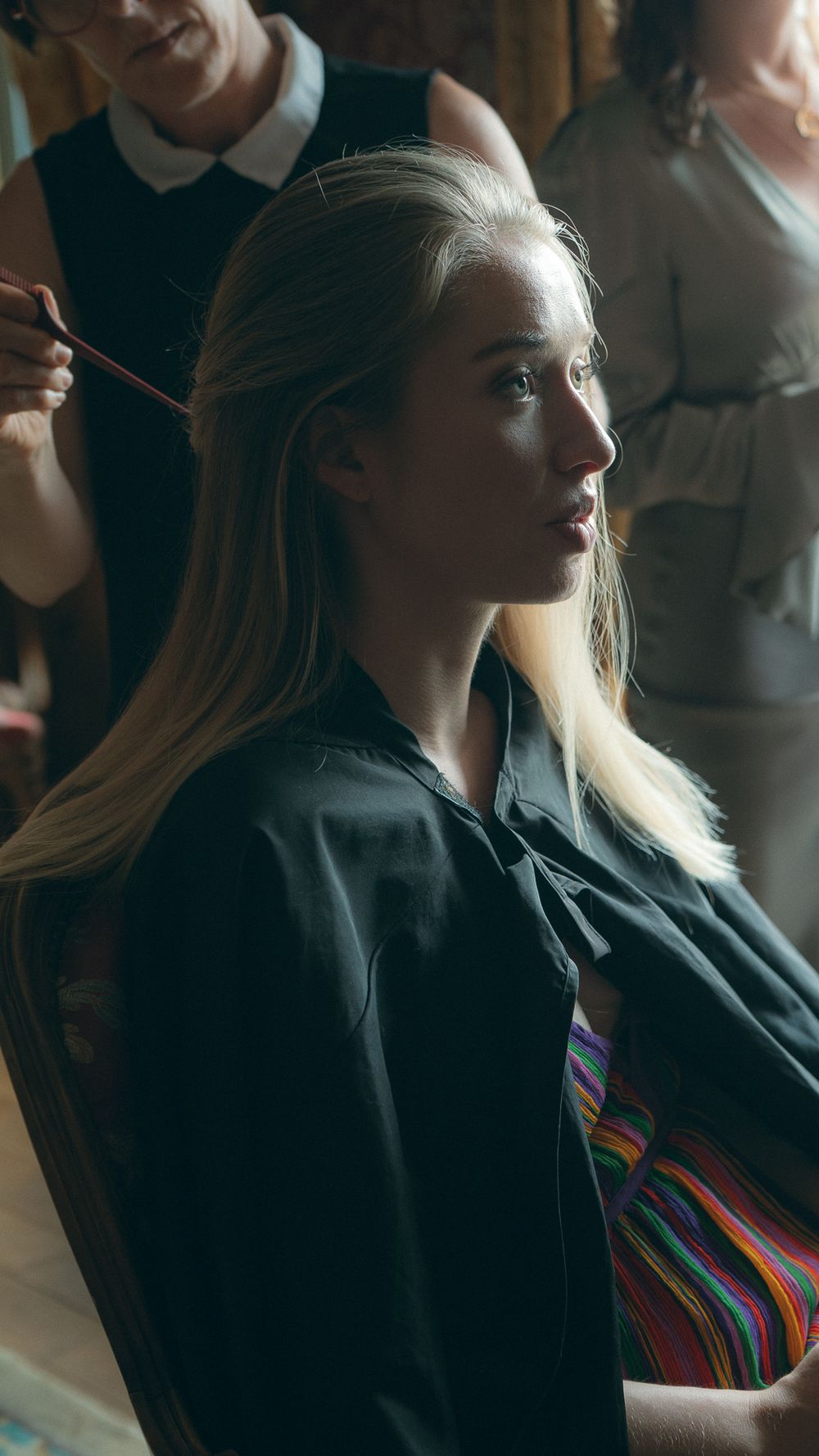 Person in black jacket with blonde hair in profile against dark background.