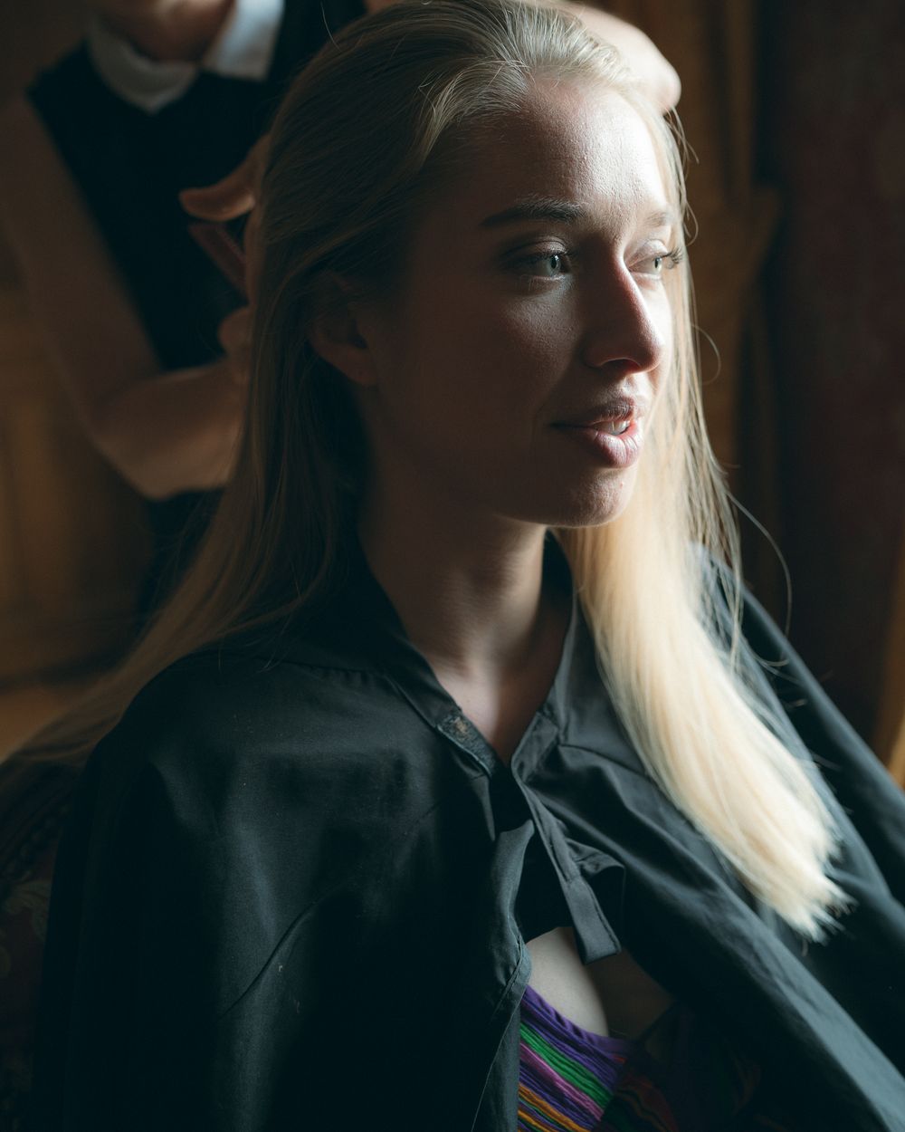 Side profile shot in moody lighting showing blonde hair and black attire.