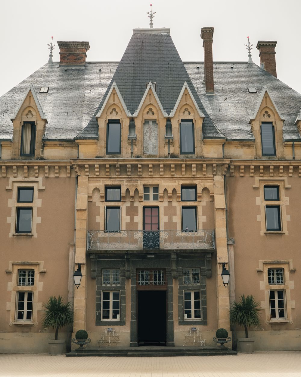 Gothic revival mansion with ornate dormers and symmetrical architecture in beige stone.