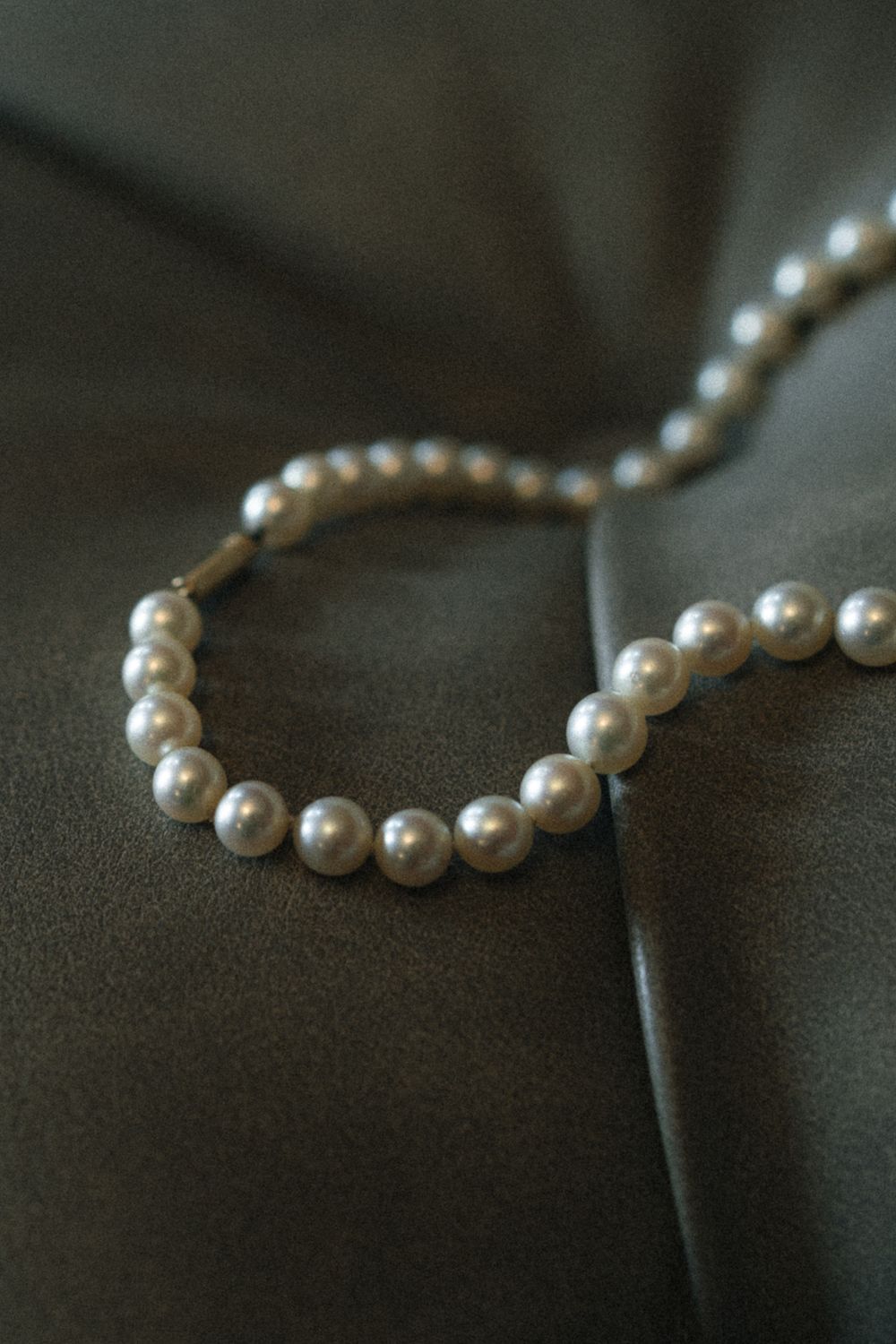 String of elegant white pearls arranged on dark fabric.