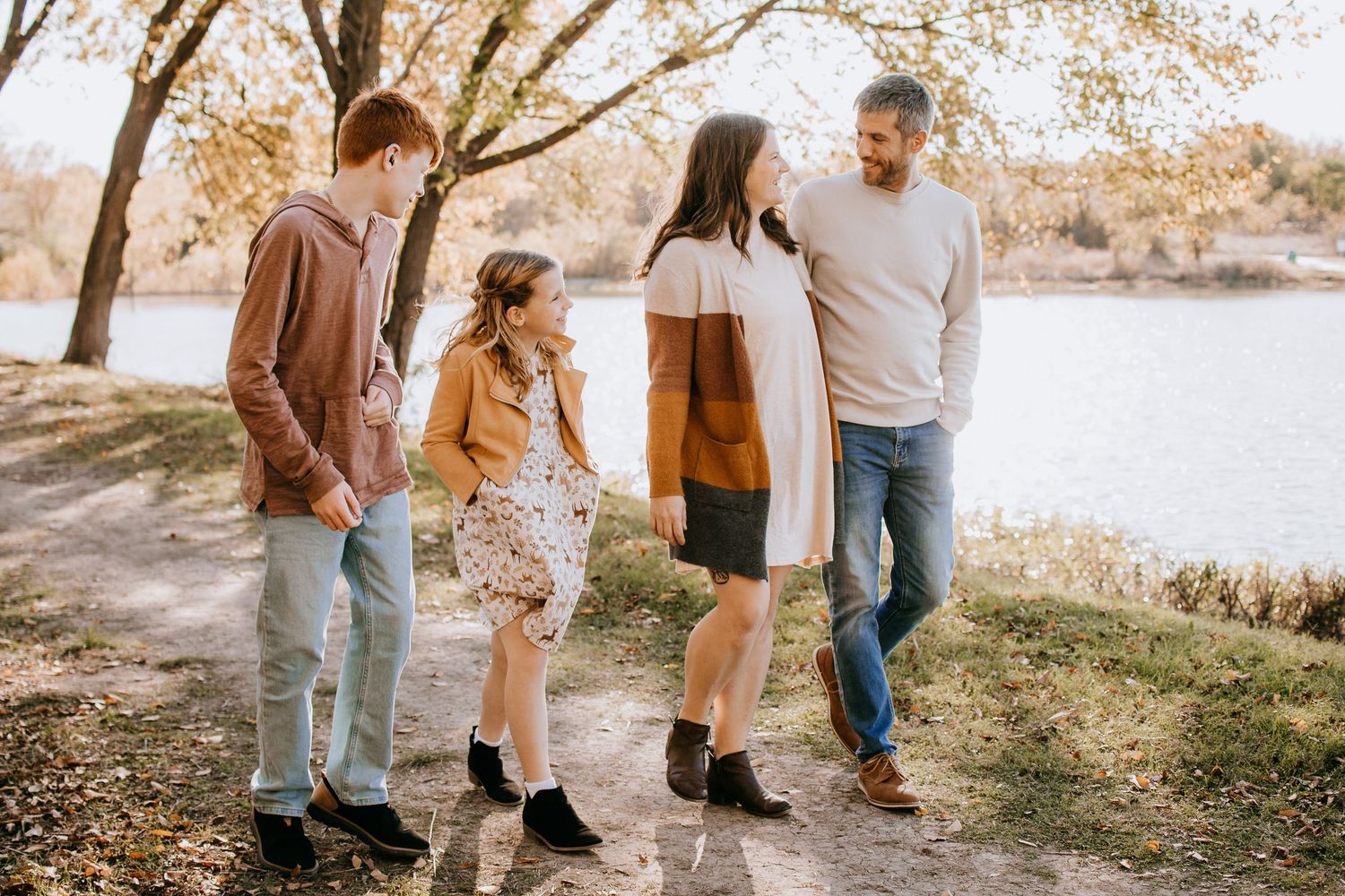 A casual family strolling together on a path by the lake in autumn weather.