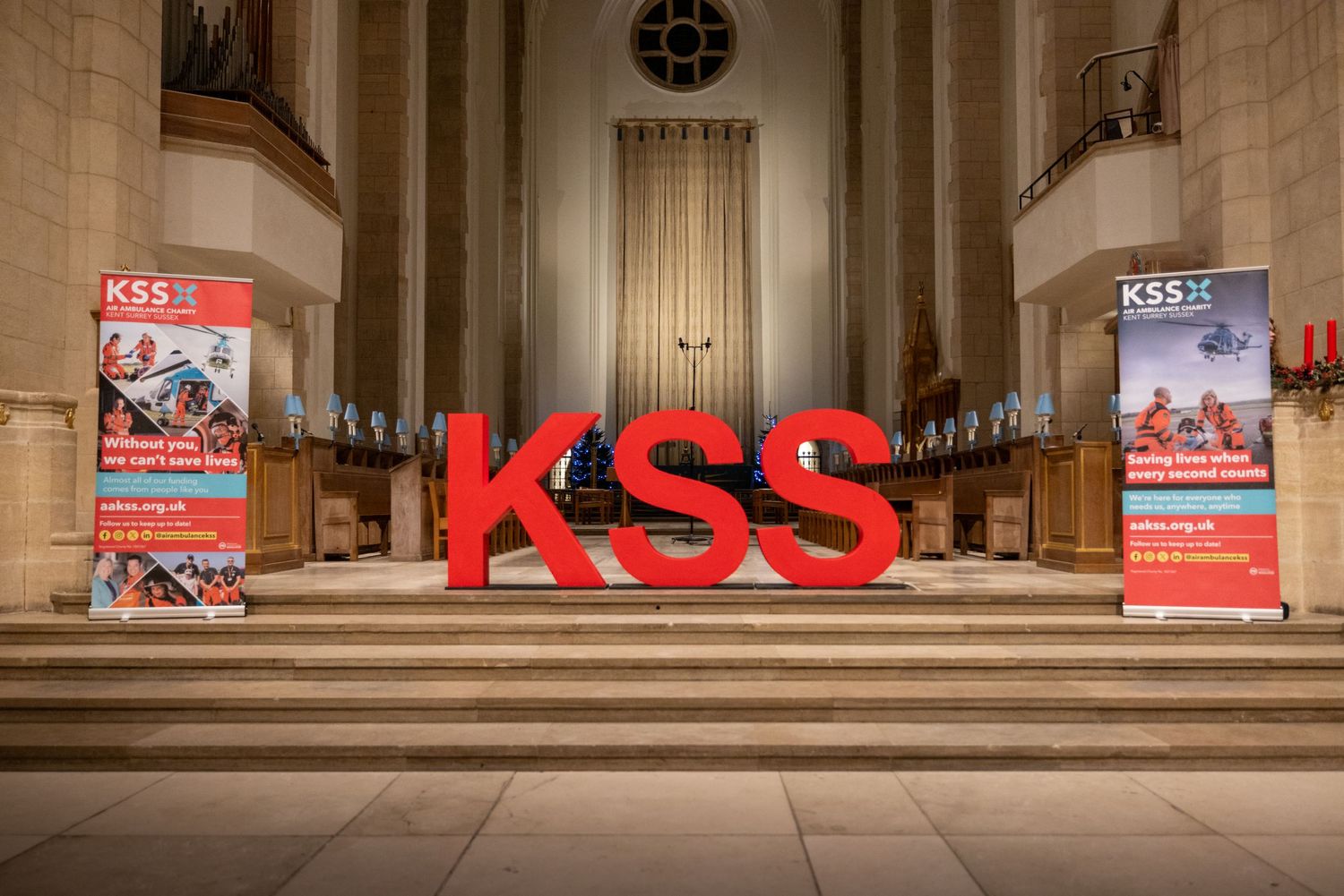 Large red KSS letters displayed on church steps with event banners on either side.