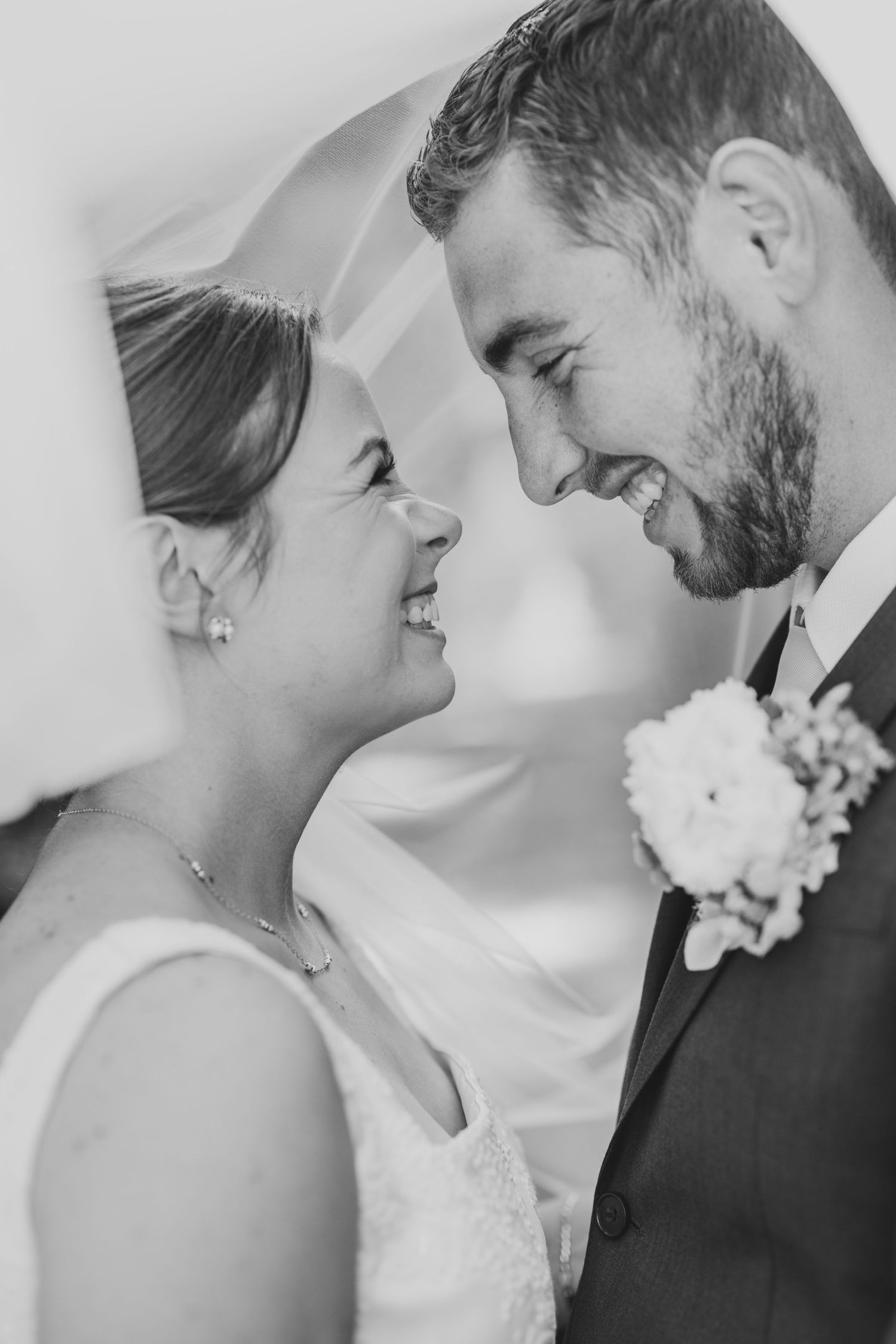Black and white close up photo of a bride and groom sharing an intimate moment beneath her veil on their wedding day.