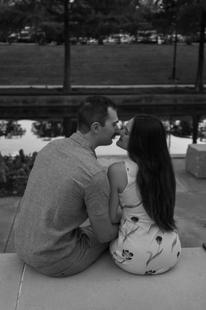 A couple shares romantic moments while sitting together outdoors in black and white photography in the Woodlands, Texas