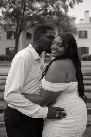 A romantic black and white portrait of a couple embracing outdoors.